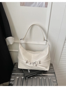 Detail of cream leather shoulder bag with decorative eyelet strap and T-bar metal buckle