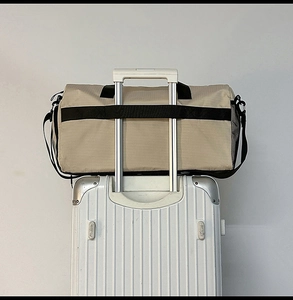 Detail of travel duffel bag showing the trolley sleeve attached to a silver suitcase