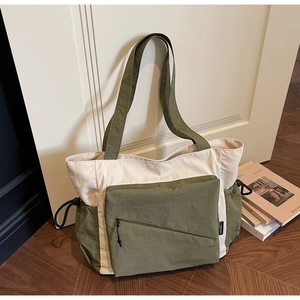 Detail of army green and beige canvas tote with side drawstring pocket and diagonal zipper