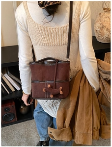 Detail of dark brown suede bucket bag with contrast stitching and plush puppy charm