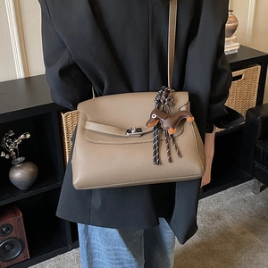 Detail of brown lychee leather tote with cute dachshund charm and metallic buckle closure