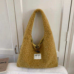 Détail d'un sac fourre-tout jaune pelucheux avec fermoir à bascule et étiquette