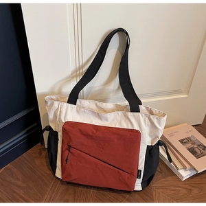 Detailed close-up of a three-color patchwork canvas tote bag with drawstring side pockets