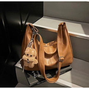Detail of vintage brown hobo bag with adjustable strap and cute plush bear charm