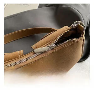 Detail of silver metal zipper and stitched brown lychee leather on a shoulder bag