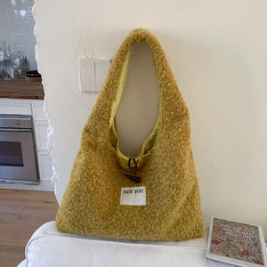 Détail du sac fourre-tout jaune moutarde en peluche avec bouton à bascule et doublure à carreaux