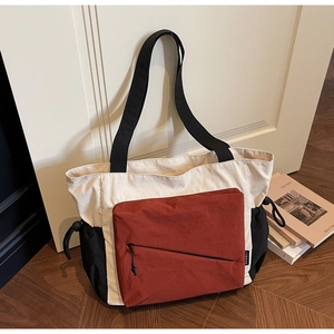 Detail of tricolor canvas tote bag with brick red front zipper pocket and side drawstrings
