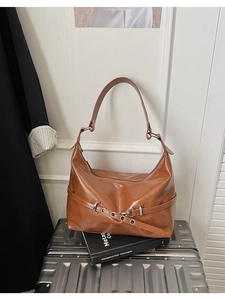 Close-up of caramel brown hobo bag featuring glossy faux leather and buckle strap