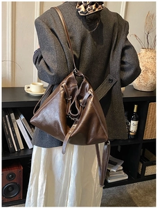Detail of dark brown leather tote bag with white contrast stitching and slim shoulder strap