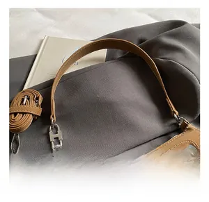 Close-up of vintage brown shoulder bag with silver H-shaped metal buckle and rivet pockets