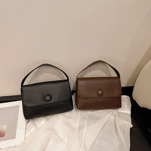 Detail of minimalist small square handbags in black and brown with round metal buckles