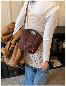 Detail of vintage brown suede bucket bag with a cute plush dog pendant and crossbody strap