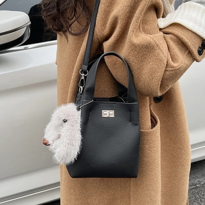 Detail of black pebbled leather bucket bag with silver lock and plush rabbit charm