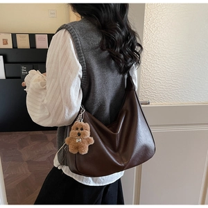 Detail of dark brown leather hobo bag with teddy bear charm in a chic home setting