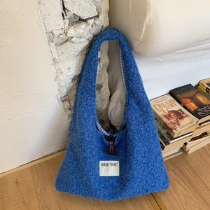 Détail du sac hobo en peluche bleue avec boucle en bois et doublure à carreaux