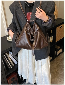 Detail of dark brown leather backpack with white contrast stitching and minimalist design