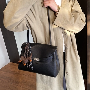 Detailed shot of black lychee leather tote bag with silver lock and puppy charm decoration