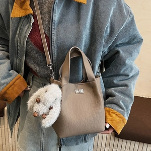 Close-up of lychee grain bucket bag with silver clasp and plush rabbit pendant