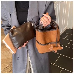 Detail of brown leather zipper pouch and suede bucket bag with contrast stitching