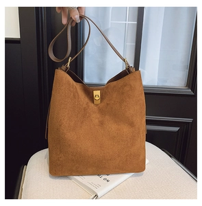 Detailed close-up of brown suede bucket bag featuring a gold rectangular twist lock closure