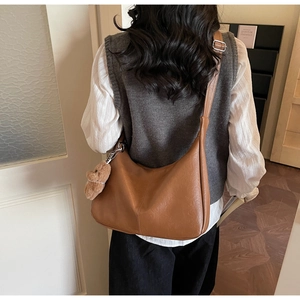 Detailed back view of a brown crescent shoulder bag with a cute bear plush charm