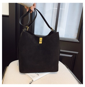 Close-up of black matte suede bucket bag with gold clasp and versatile straps