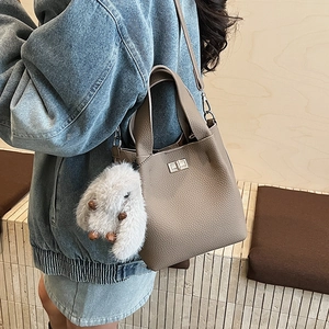 Detail of dark apricot bucket bag with silver twist lock and plush rabbit charm