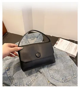 Detail of a chic black leather handbag with a flap closure and round button fastener
