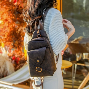 Primer plano de un bolso de pecho vintage de cuero marrón con hebillas de correa decorativas
