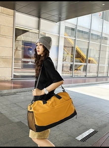 Detail of a large yellow and black travel bag featuring side mesh pocket and sturdy straps