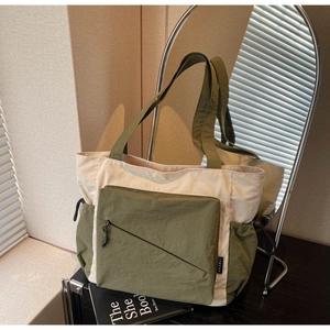 Detail of two-tone tote bag featuring olive green zipper pocket and durable nylon texture
