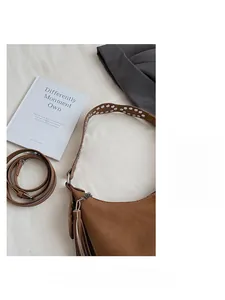 Detail of caramel crescent bag featuring silver studs on strap and fringe tassels