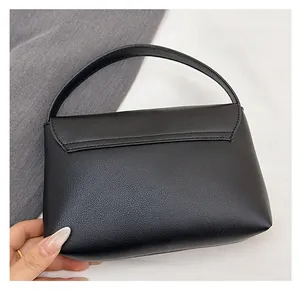 Close-up of black leather handbag featuring fine litchi texture and minimalist stitching