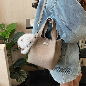 Detail of grey lychee leather bucket bag with silver twist lock and plush hedgehog charm