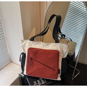 Detail of color-block tote bag with side drawstring pocket and front zipper on canvas