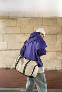 Model display of a large beige travel bag showing practical shoulder strap usage