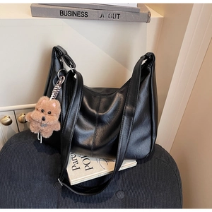 Macro shot of black leather underarm bag with decorative stitching and a cute dog charm