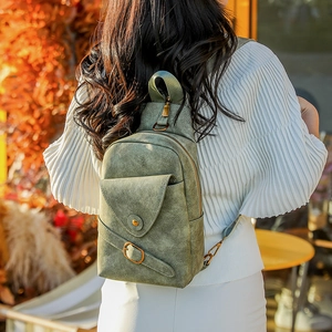 Detalle del bolso bandolera vintage verde oscuro con textura de ante y hebilla de bronce