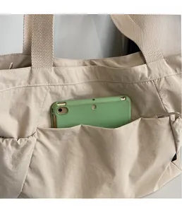 Detail of the multi-pocket tote bag showing the exterior compartment for smartphone storage