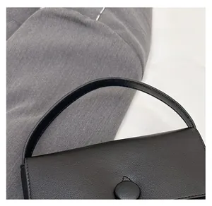 Close-up of black leather handbag featuring round buckle and comfortable handle