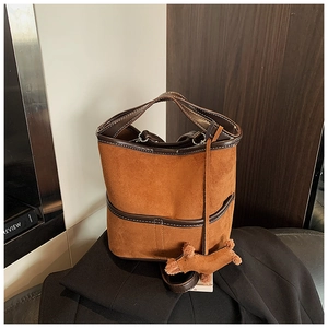 Detailed view of brown suede bucket bag with white contrast stitching and puppy charm