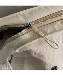 Detailed close-up of a sturdy zipper with extended puller on a beige canvas tote bag