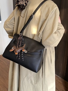 Classic black pebbled leather tote bag with silver lock and dog charm on khaki trench coat