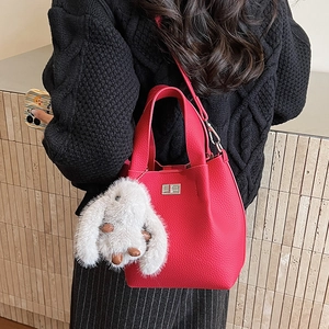 Detail of rose red bucket bag with litchi texture and cute white bunny charm accessory