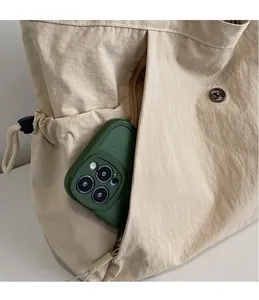 Detail view of a beige canvas tote bag side pocket holding a smartphone for storage scale