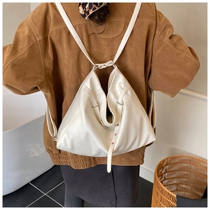 Detail of a large white faux leather tote bag with metal rings shown on a model