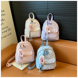 Detail of colorful tweed mini backpacks with tassel horse charms and woven texture