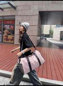 Detail of pink travel bag with black mesh pocket and shoulder strap in outdoor use