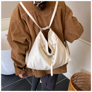 Detail of a minimalist cream-colored PU leather backpack showing its soft folded design