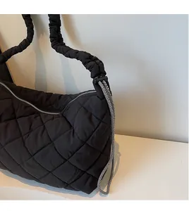 Detail of quilted nylon bag showing ruched shoulder strap and decorative drawstring